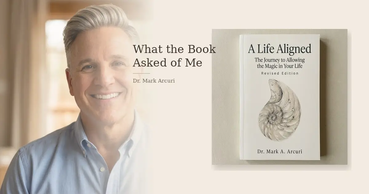 Dr Mark's Musings 5 Dr. Mark Arcuri smiling warmly beside the cover of his book A Life Aligned: The Journey to Allowing the Magic in Your Life, Revised Edition, with the title What the Book Asked of Me